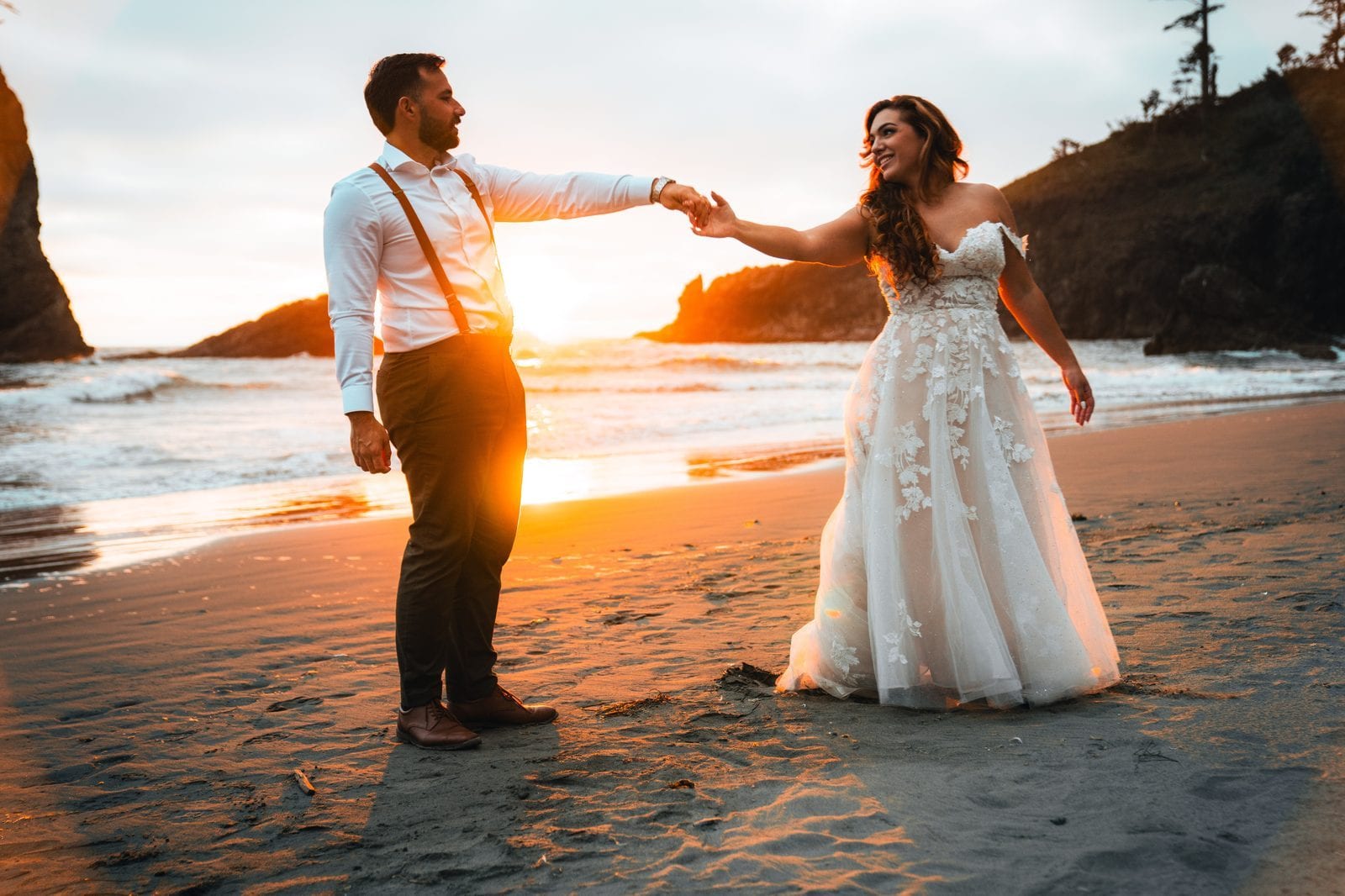 The couple holding hands on the beach at sunset