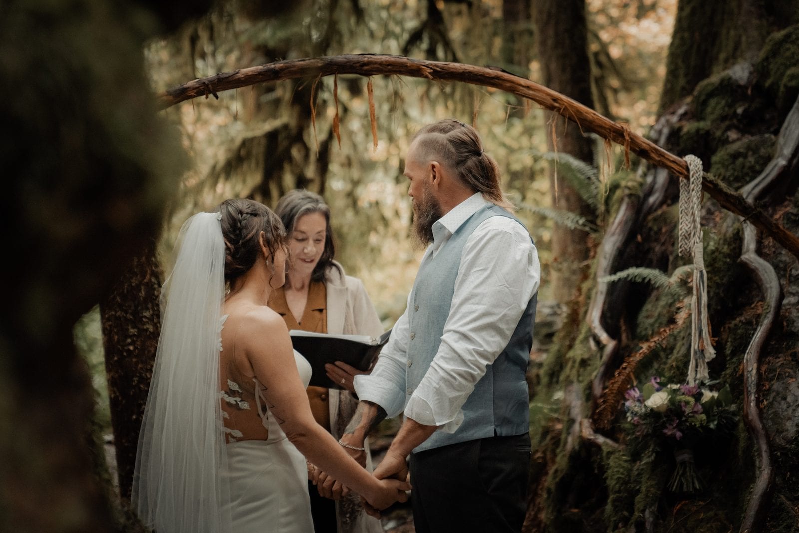 The couple kissing under the branch arch