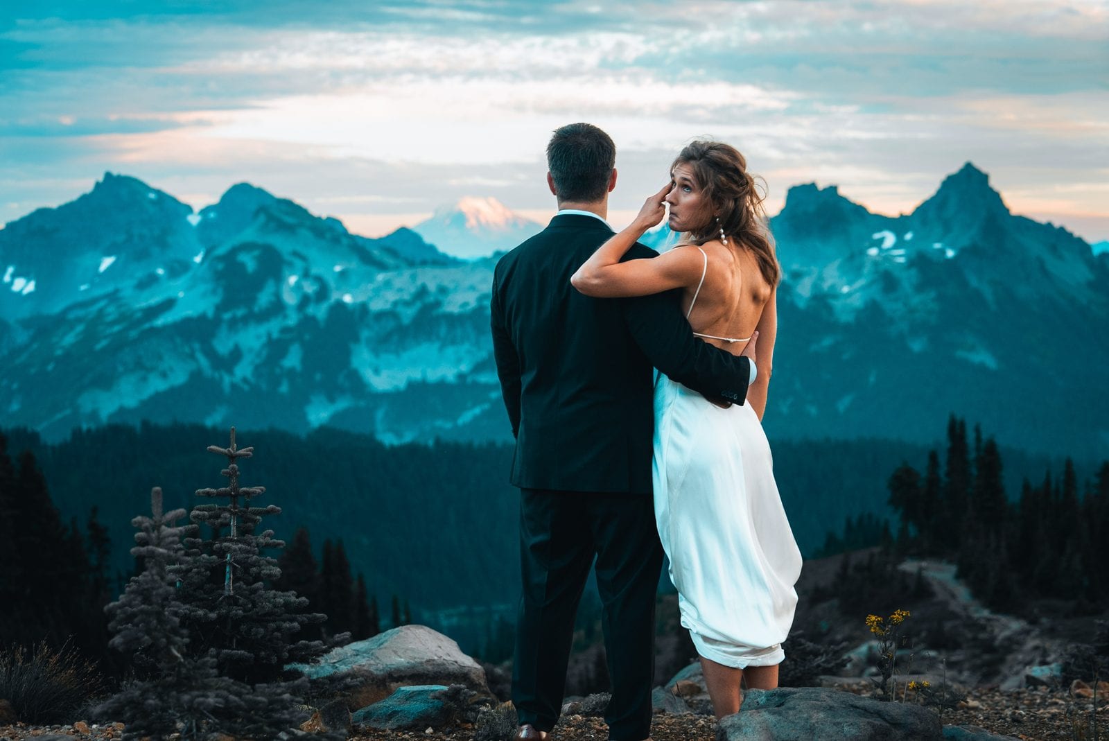 The bride glancing back, mountains at dusk