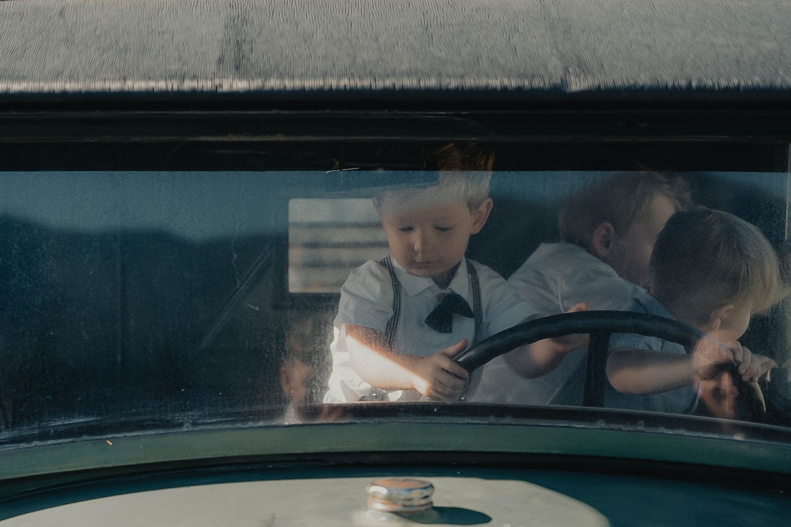 Children playing in a vintage car at golden hour