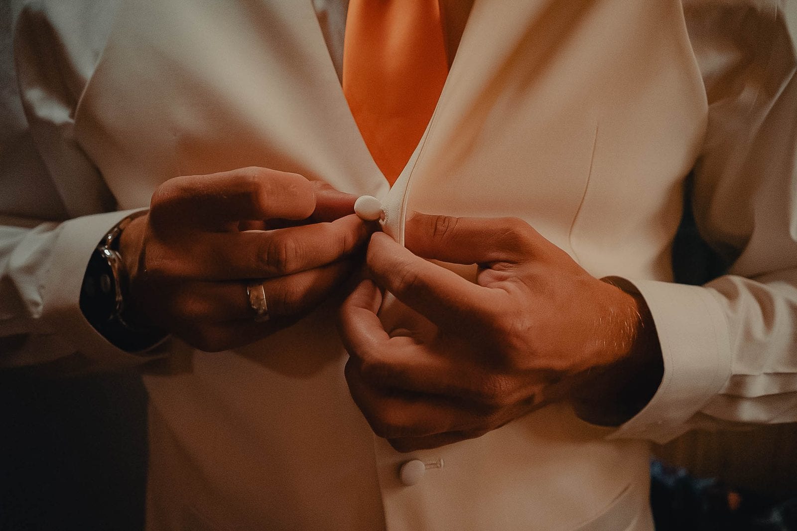 The groom buttoning his vest