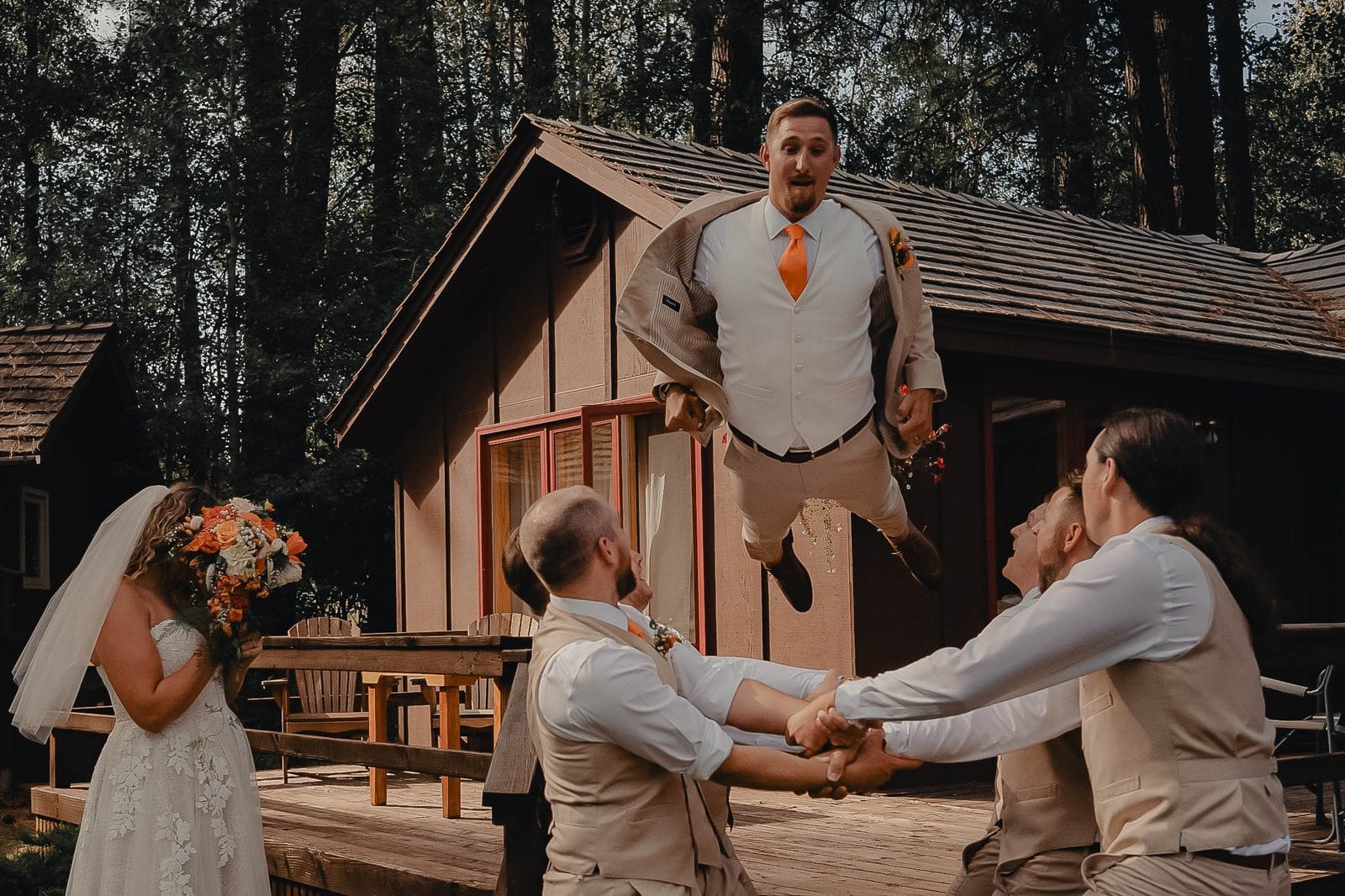 The groomsmen tossing the groom in the air