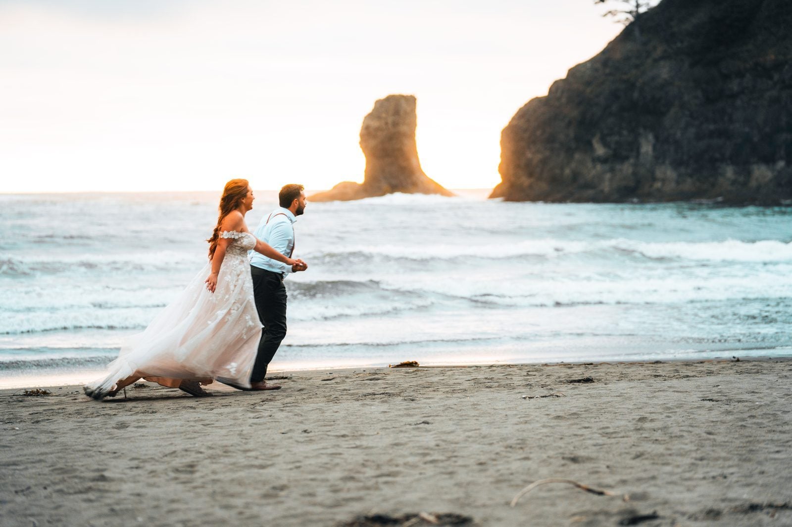 Jose and Alyah walking the black-sand coast at sunset on their elopement day